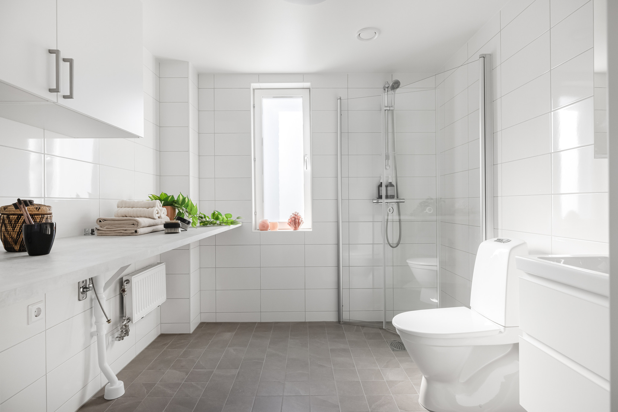 Ett ljust badrum med toalett, handfat och dusch.